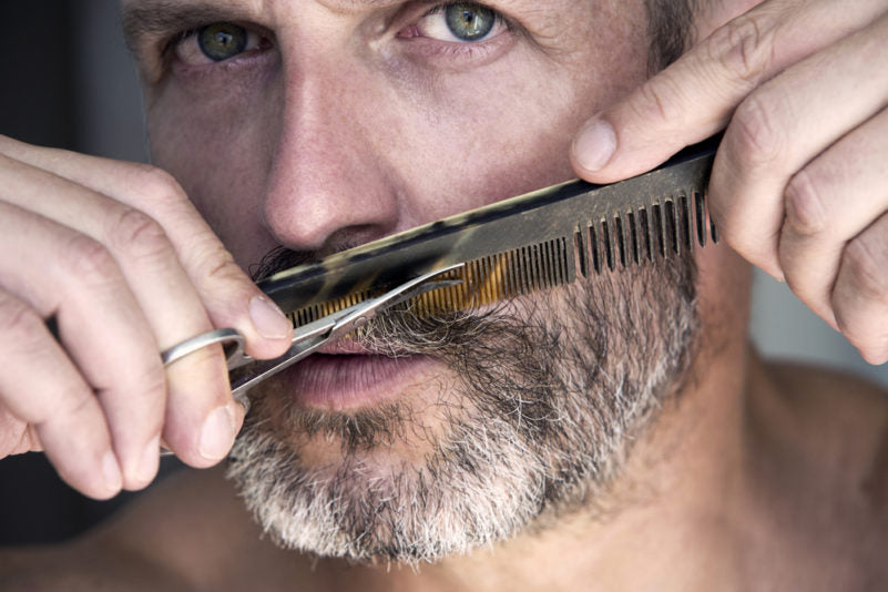 Man trimming his beard with scissors